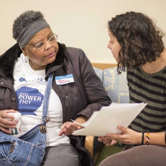 two women speaking with an open folder